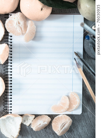 Empty notebook pages and tangerines 76030935