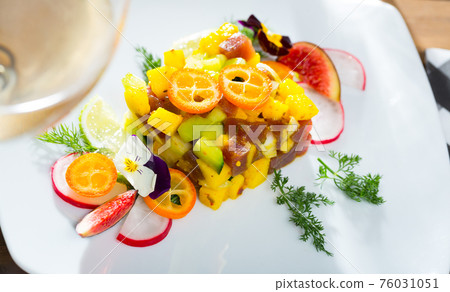 Tasty tuna tartare with mango and avocado, served with fig and flower Tasty tuna tartare with mango and avocado, served with fig and flower 76031051