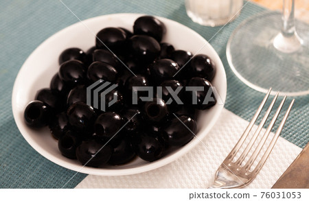 Pickled black olives in white bowl 76031053