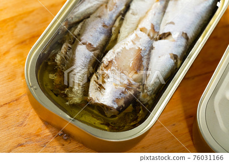 Open can of sardines on table 76031166