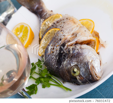 Top view of whole grilled dorada served with lemon and greens at plate Top view of whole grilled dorada served with lemon and greens at plate 76031472