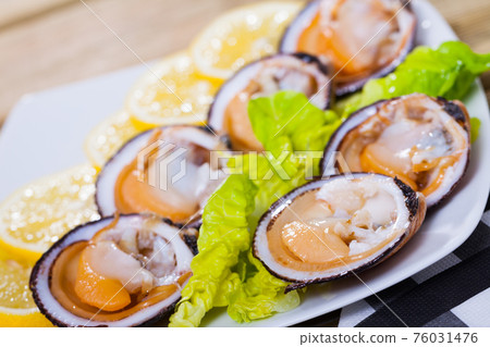 Image of salad of raw dog cockle with lemon and fresh greens 76031476