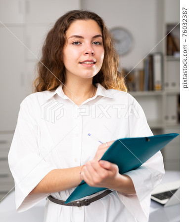 Portrait of smiling young woman holding folder 76032387