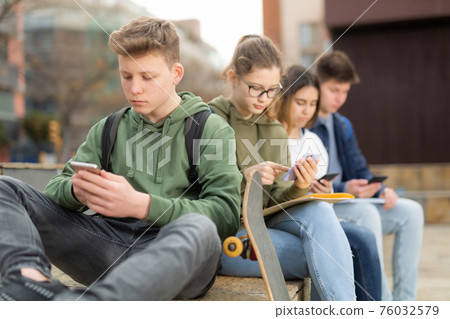 Teenage friends holding phones 76032579