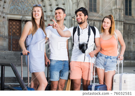 four happy travelers holding map in hands and looking for their way in european town four happy travelers holding map in hands and looking for their way in european town 76032581