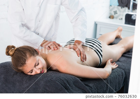 Woman massage therapist massaging relaxing young woman Woman massage therapist massaging relaxing young woman 76032630