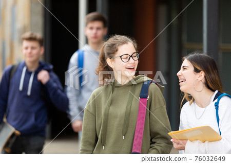 Smiling teenage girls walking after lessons Smiling teenage girls walking after lessons 76032649