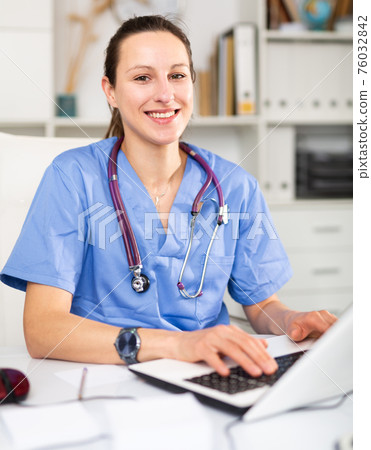 Woman doctor sitting at workplace with computer in office Woman doctor sitting at workplace with computer in office 76032842