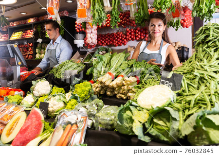 Female seller offering vegetables on market Female seller offering vegetables on market 76032845