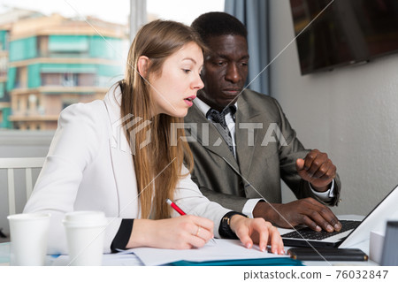 Man and woman managers with laptop working and discussing Man and woman managers with laptop working and discussing 76032847