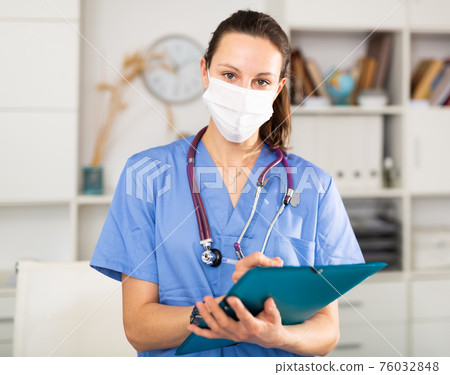 Portrait of female doctor in protective mask with folder in clinic Portrait of female doctor in protective mask with folder in clinic 76032848