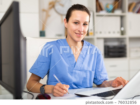 Woman doctor sitting at workplace with computer in office Woman doctor sitting at workplace with computer in office 76032856