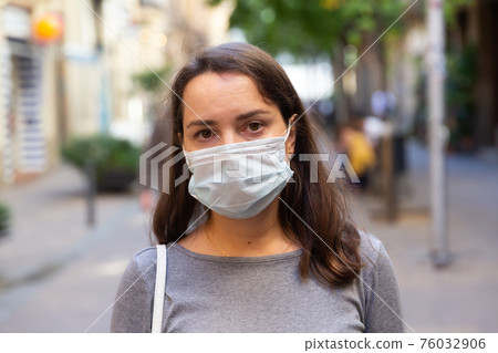 Closeup face of woman in protective mask on city street Closeup face of woman in protective mask on city street 76032906