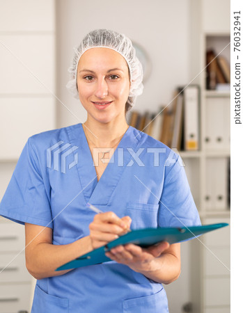 Positive woman doctor in formal wear standing with folder 76032941