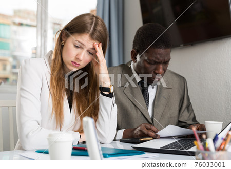 Tired managers during work with documents and laptop at office Tired managers during work with documents and laptop at office 76033001