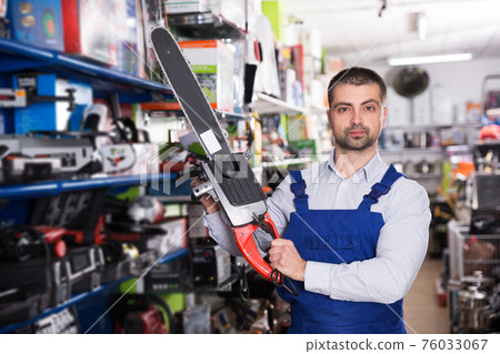 male is standing with new electric saw male is standing with new electric saw 76033067