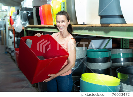 Female customer holding big decorative plastic vase for flowers 76033472