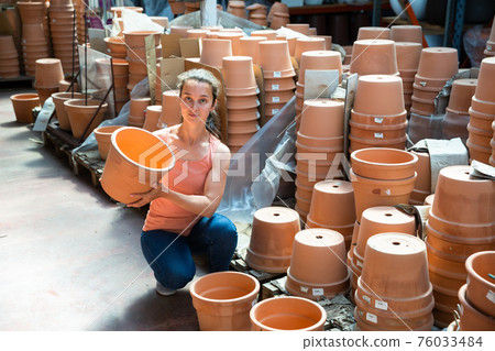 Young woman customer looking decorative clay pot for garden Young woman customer looking decorative clay pot for garden 76033484