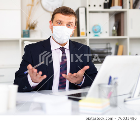 Manager in disposable mask discussing in office 76033486