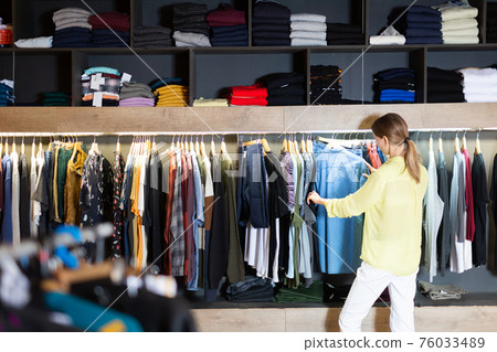 Young woman choosing male clothes in store Young woman choosing male clothes in store 76033489