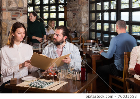 Happy couple with menu at country restaurant 76033558