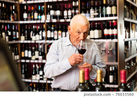 Elderly man smells the quality of red wine 76033560