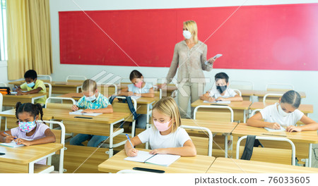 Focused kids in masks working at class 76033605