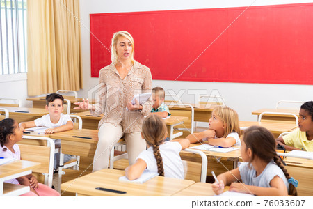 Teacher communicates freely with students in classroom at elementary school Teacher communicates freely with students in classroom at elementary school 76033607