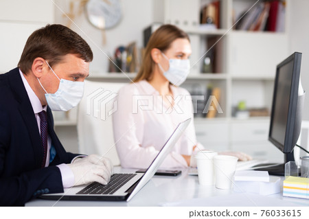 Manager in medical mask working with female colleague in office 76033615