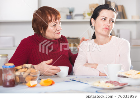 Portrait of sad mature woman talking with daughter Portrait of sad mature woman talking with daughter 76033959
