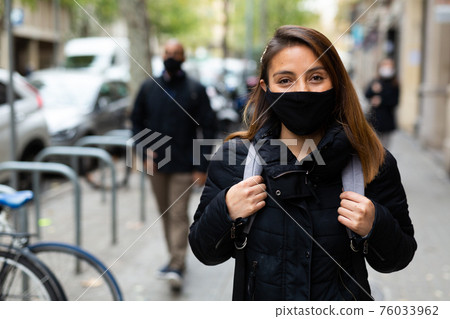 Positive woman in face mask walking outdoors Positive woman in face mask walking outdoors 76033962