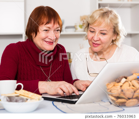 Two smiling elderly women using laptop Two smiling elderly women using laptop 76033963