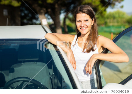 Woman standing near car at sunny day 76034019