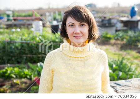 Girl in a yellow sweater works in the garden of a country house 76034056