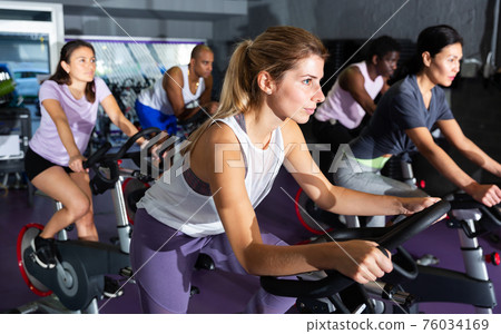 Woman training on stationary bike in gym Woman training on stationary bike in gym 76034169