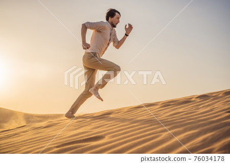 The person overcomes difficulties and aspires to the purpose and dream. A man overcomes difficulties in life as if in a desert The person overcomes difficulties and aspires to the purpose and dream. A man overcomes difficulties in life as if in a desert 76034178