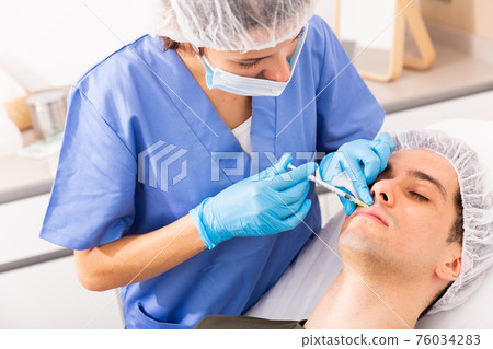 Male patient getting face injections 76034283