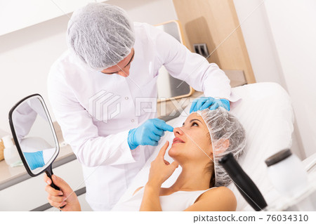 Cosmetologist giving consultation to woman patient Cosmetologist giving consultation to woman patient 76034310