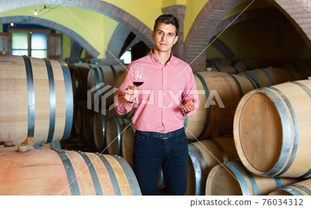Male customer tasting red wine from wooden barrels Male customer tasting red wine from wooden barrels 76034312