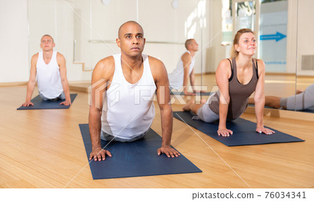 Man making yoga exercises at group class Man making yoga exercises at group class 76034341