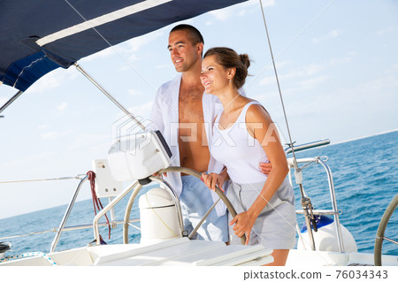 Man and woman steering pleasure yacht 76034343
