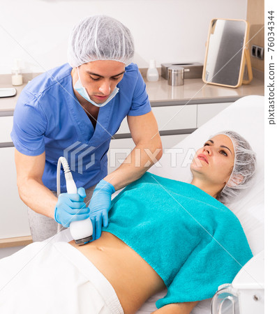 Woman receiving body ultrasound lifting procedure Woman receiving body ultrasound lifting procedure 76034344