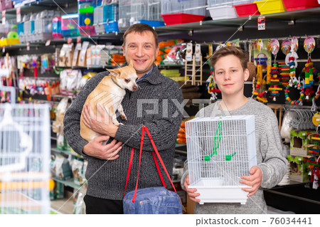 Happy man with teenager son and little dog buying pet supplies Happy man with teenager son and little dog buying pet supplies 76034441