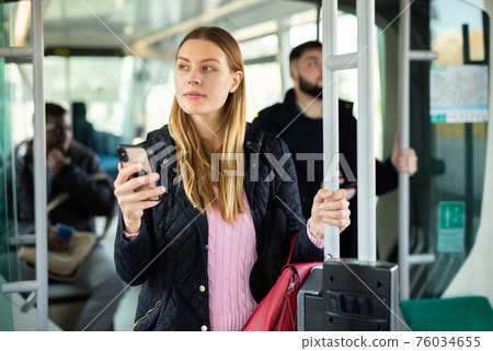 Woman using phone in city bus 76034655