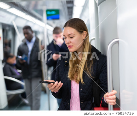 Girl using mobile phone in metro car 76034739