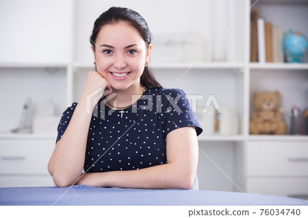 Smiling brunette sitting at table 76034740