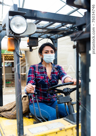 woman in protective face mask working on forklift woman in protective face mask working on forklift 76034746