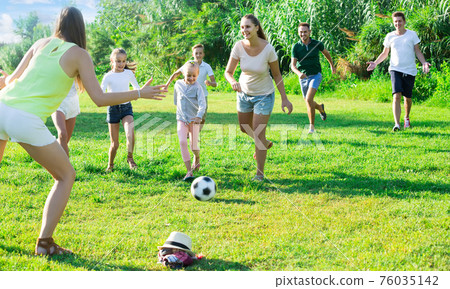Two friendly families with children playing football in nature at summer Two friendly families with children playing football in nature at summer 76035142