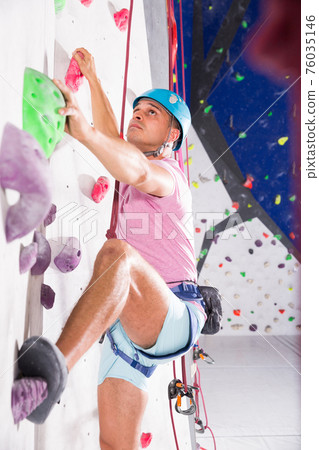 Man in climbing outfit training at bouldering gym Man in climbing outfit training at bouldering gym 76035146