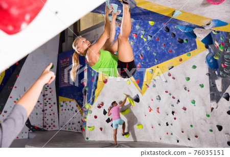 Young sporty woman training at bouldering gym without special climbing equipment Young sporty woman training at bouldering gym without special climbing equipment 76035151